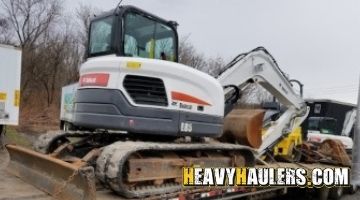 Strapping a Bobcat excavator for transport.