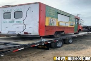 Loading a pizza truck on a flatbed trailer.