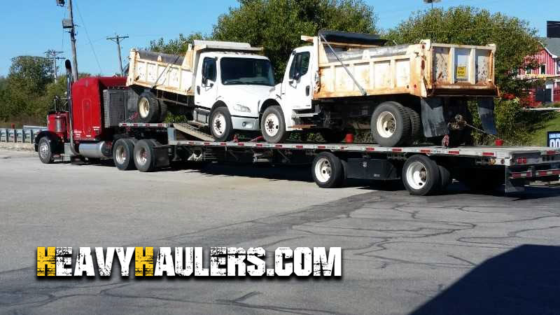 Transporting two garbage trucks on a trailer.