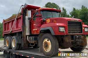 2003 Mack truckloaded on a trailer.