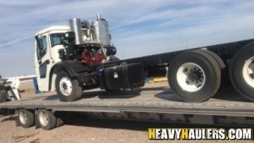 Flatbed truck shipped on a flatbed trailer.